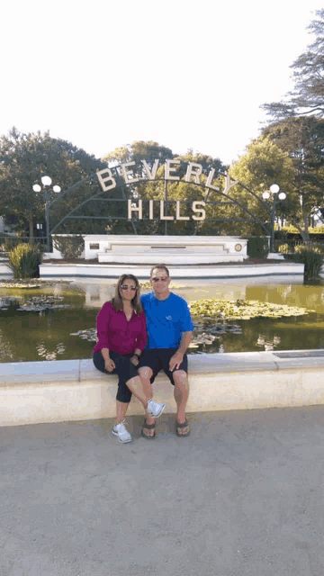 a man and a woman pose in front of a sign that says beverly hills