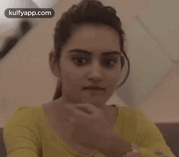 a woman is sitting on a couch with her mouth open and a ponytail .