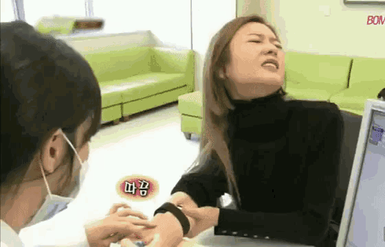 a woman is getting a blood sample from a doctor while wearing a mask .