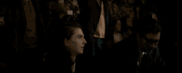 a group of people are sitting in a dark room and watching a movie .