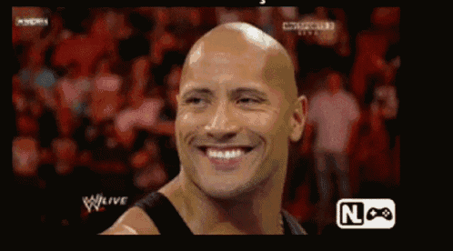 a bald man is smiling in front of a crowd while watching a w live event