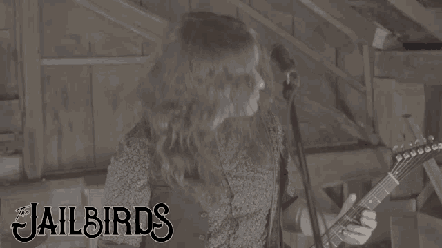 a woman singing into a microphone while playing a guitar with the jailbirds written on the bottom