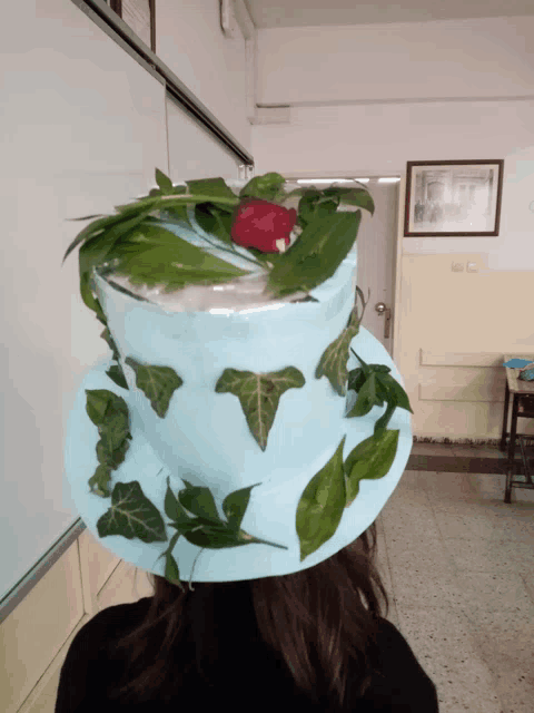 a person wearing a blue top hat with leaves and a red rose on top