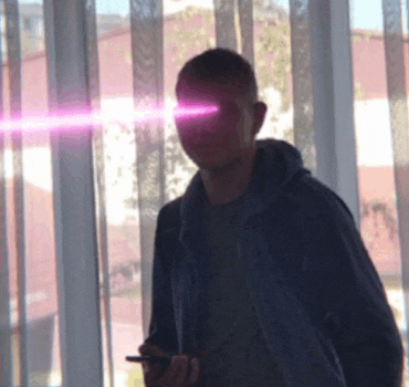 a man is standing in front of a window with a purple light coming out of his eyes