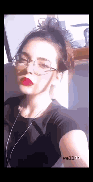 a woman wearing glasses and red lipstick is taking a selfie with her phone .