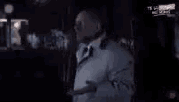 a man in a suit and tie is walking down a street at night .
