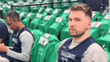 a man in a dallas jersey is sitting in a stadium with green seats .