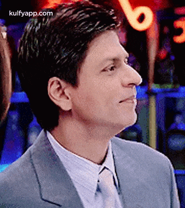 shah rukh khan is wearing a suit and tie and looking up .