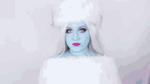 a woman with blue paint on her face and white hair is wearing a fur hat and a fur coat .