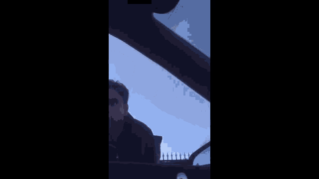 a man is sitting in the driver 's seat of a car looking out the window at a sign .
