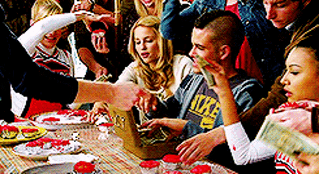 a group of people are gathered around a table with a man wearing a nike sweatshirt