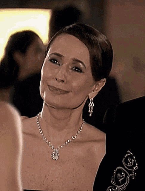a woman wearing a necklace with the letter g on it smiles