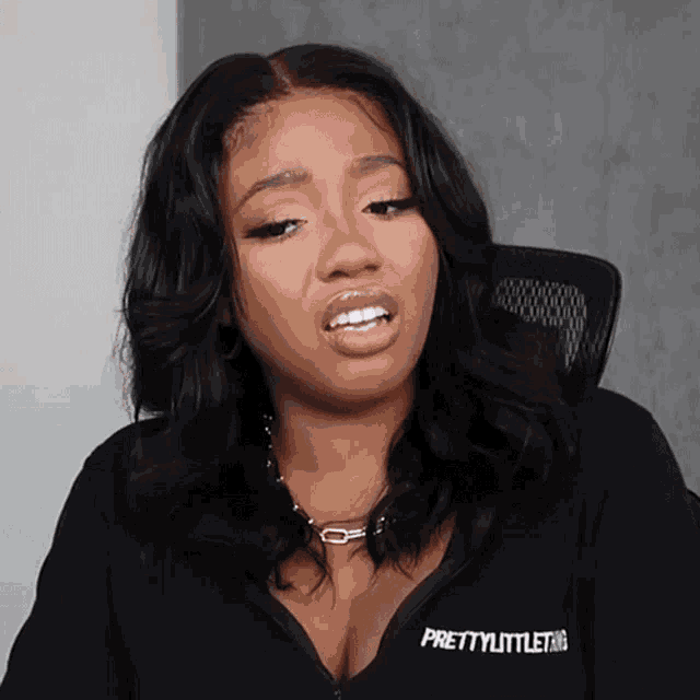 a woman wearing a black prettylittlething shirt makes a funny face