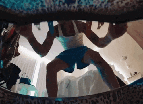 a man in a white tank top and blue shorts stands in front of a leopard print wall