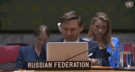 a man sits in front of a laptop with a sign that says russian federation
