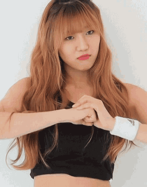a woman wearing a black crop top and a white wristband with the word adidas on it