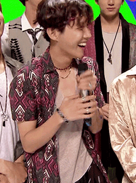 a man in a floral shirt is holding a microphone and laughing