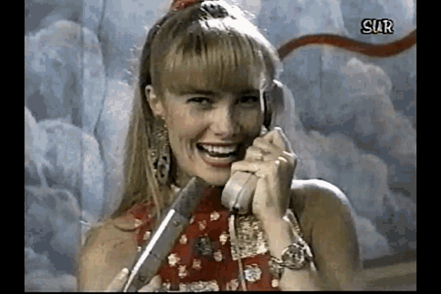 a woman is smiling while talking on a phone with the word sur written on the bottom