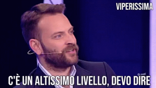 a man with a beard is talking into a microphone with the words " c ' e un altissimo livello devo dire "