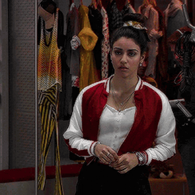 a woman in a red and white jacket stands in front of a closet full of clothes