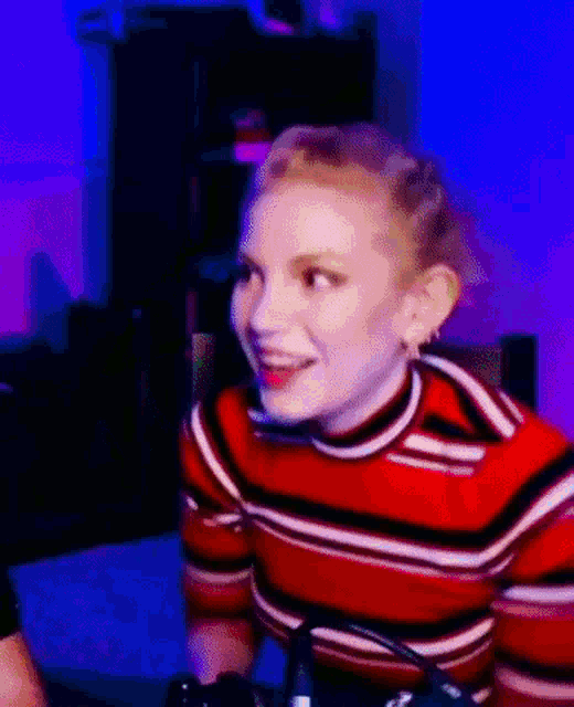 a woman in a red striped sweater is sitting at a table with a microphone .