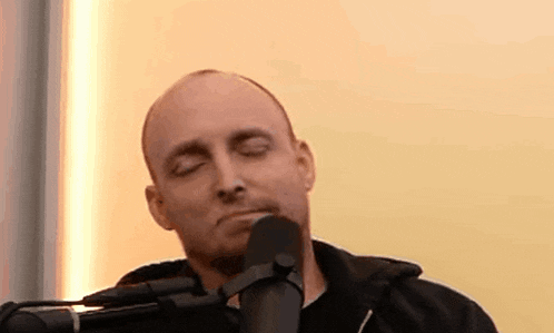 a man is singing into a microphone with his eyes closed .