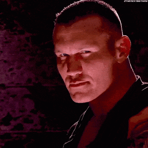 a close up of a man 's face in a dark room with a red light behind him .