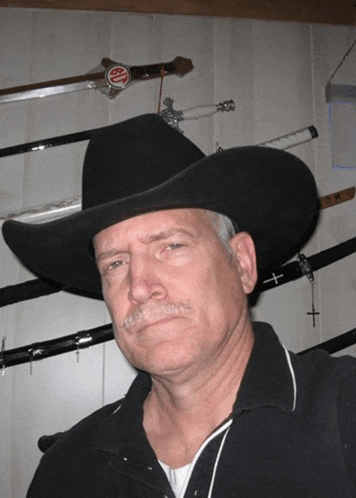 a man wearing a cowboy hat stands in front of swords