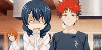 a boy and a girl are standing next to each other in a kitchen . the girl is making a funny face .
