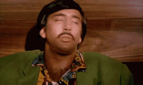 a man wearing a green jacket and a colorful shirt with his eyes closed
