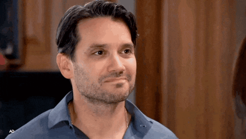 a man with a beard is wearing a blue shirt and looking at something .