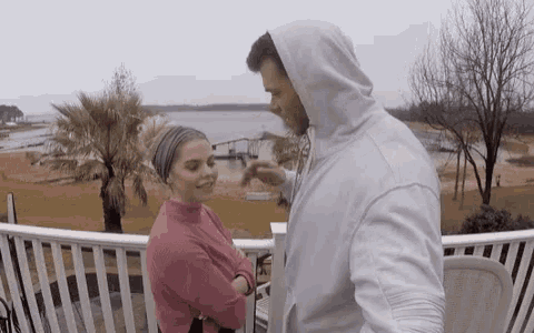 a man and a woman are standing next to each other on a balcony .