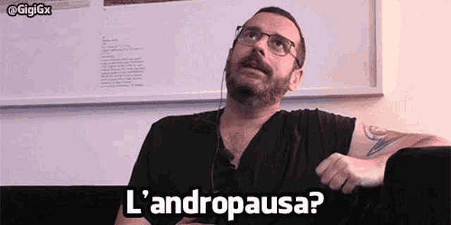 a man wearing glasses and headphones is sitting on a couch and says l' andropausa