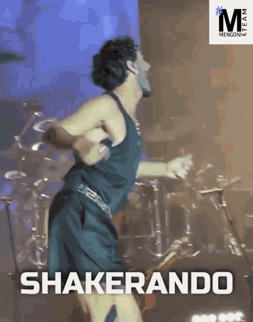 a man in a black tank top and shorts is shakerando on a stage