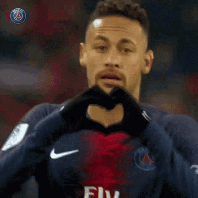 a soccer player is making a heart shape with his hands while wearing a fly emirates jersey .