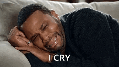a man is laying on a couch with his eyes closed and crying .