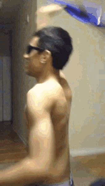a shirtless man wearing sunglasses stands in a room