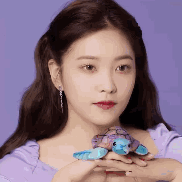 a woman holding a stuffed turtle in her hands