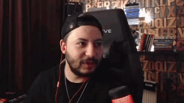 a man with a beard is sitting in front of a microphone in a room .