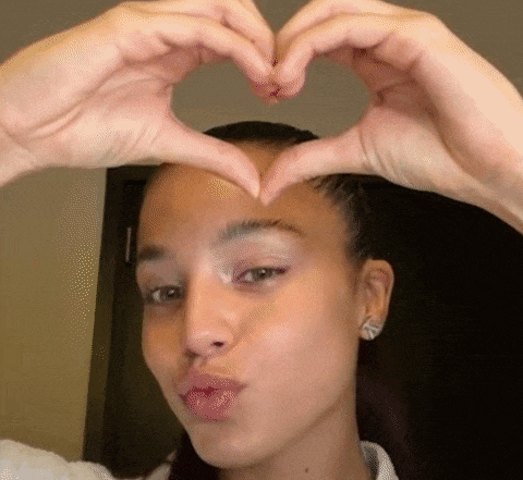 a young woman is making a heart shape with her hands .