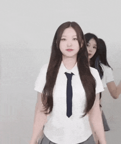 a girl in a school uniform and tie is standing with her arms outstretched and looking at the camera .