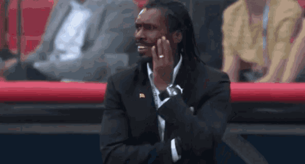 a man in a suit is sitting in a stadium with his hands on his face .