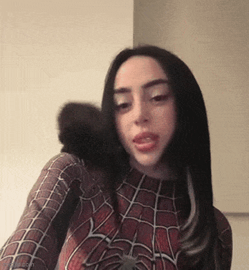 a woman in a spiderman costume is taking a selfie with a monkey on her shoulder .