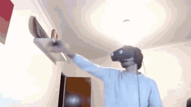 a man wearing a virtual reality headset is holding a skateboard in his hand .