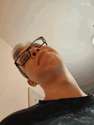 a man wearing glasses looks up at the camera .