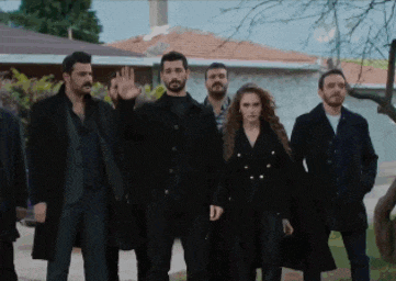 a group of men and women are standing in front of a house