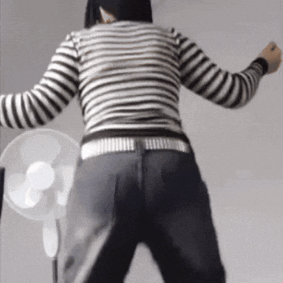 a woman in a black and white striped shirt is dancing in front of a fan