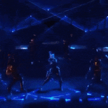 a woman in a futuristic outfit is dancing in a dark room with blue lights .