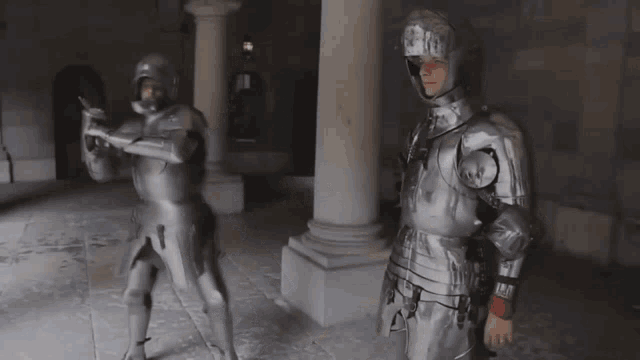 two men in armor stand next to each other in a hallway
