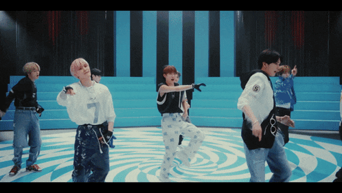 a group of young men are dancing in front of a blue and white striped backdrop